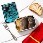 Tin of smoked trout with olive oil, packaging, bread, and fork on a marble surface