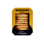 A package of Delgado Boquerones al Pimentón, featuring golden-brown bread stuffed with salami, visible through a clear window on a yellow and black box.