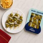 Olives on toothpicks with Delgado packaging on a white surface