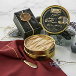 Two tins of Los Peperetes tuna belly in butter on a marble surface with decorative elements.