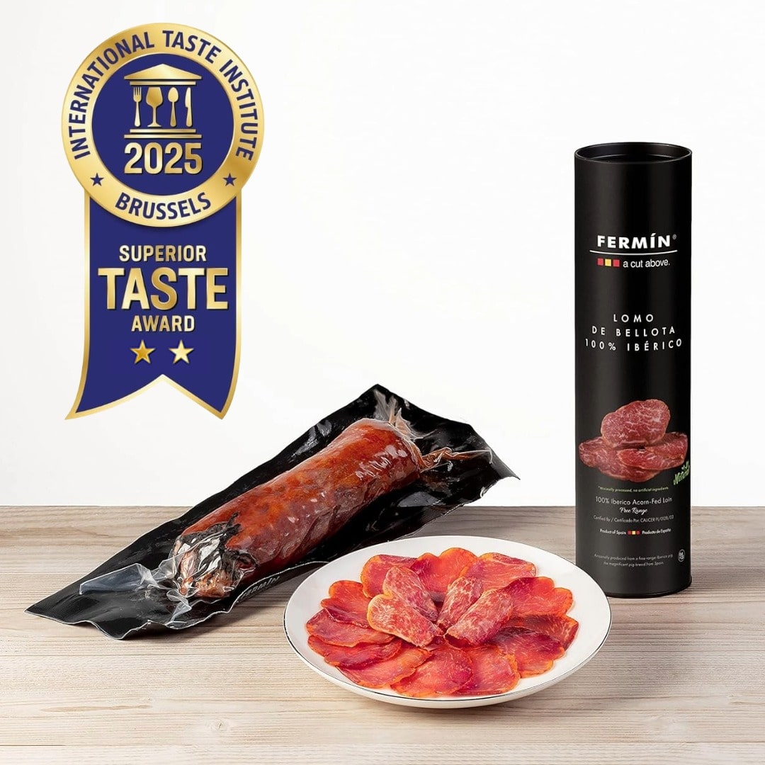 Fermin Iberico salami with packaging and a plate of sliced salami on a wooden surface, featuring the International Taste Institute award.