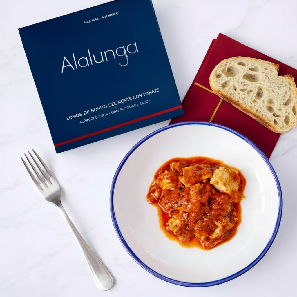 Plate of bonito in tomato sauce with a box labeled 'Alalunga' on a white background