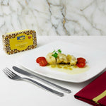 Dish of codfish on a plate with a tins of Briosa codfish and cutlery on a marble surface.