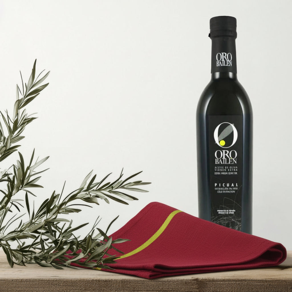 Bottle of Oro Bailen olive oil with olive branches on a wooden surface