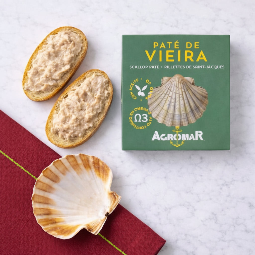 Scallops pate on bread with a green Agromar packaging on a white marble surface