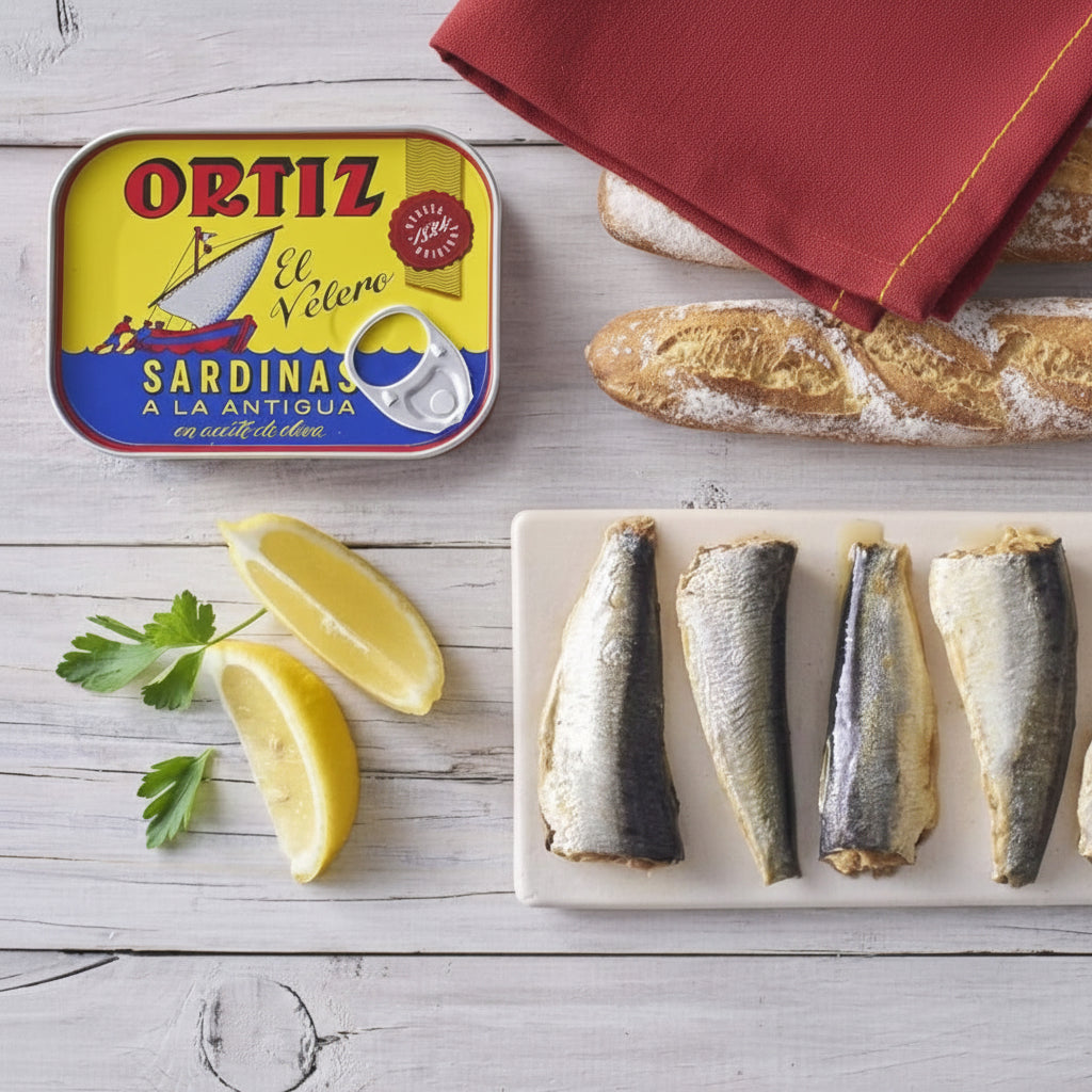Ortiz sardines can with sardines, bread, and lemon on a wooden surface