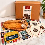 Tinned Fish Board Kit with wooden board, cards, and a box on a marble surface.