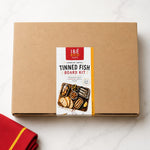 Cardboard box with a Tinned Fish Board Kit label on a white background