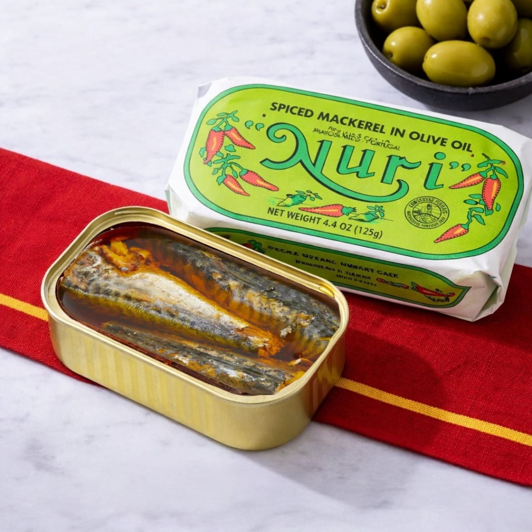 Nuri spiced mackerel in olive oil can with green label on a red and white striped cloth.