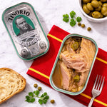 Open can of tuna with olives on a red napkin, next to a Tenerio Portugal can and bread.