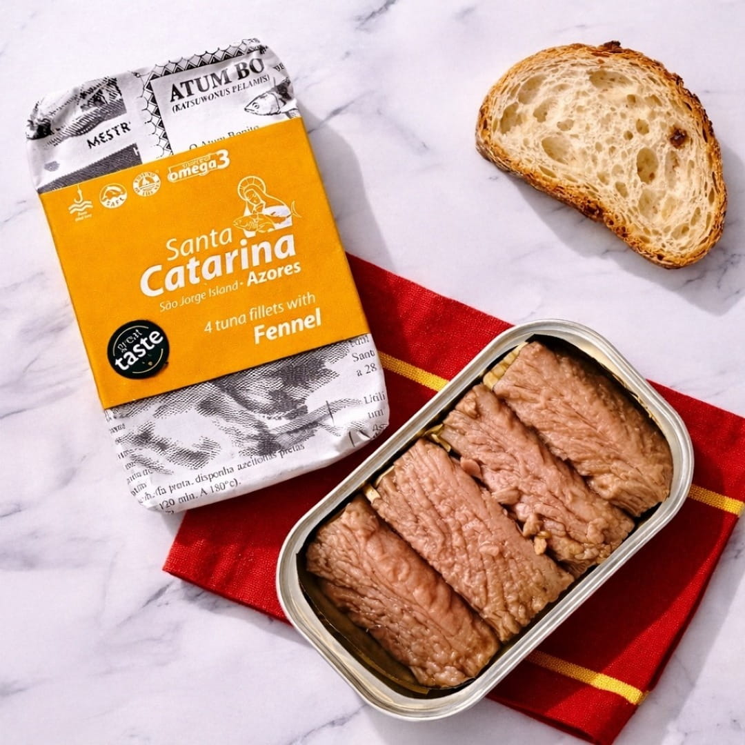 Tuna fillets with fennel in a can on a red napkin with packaging and bread in the background.